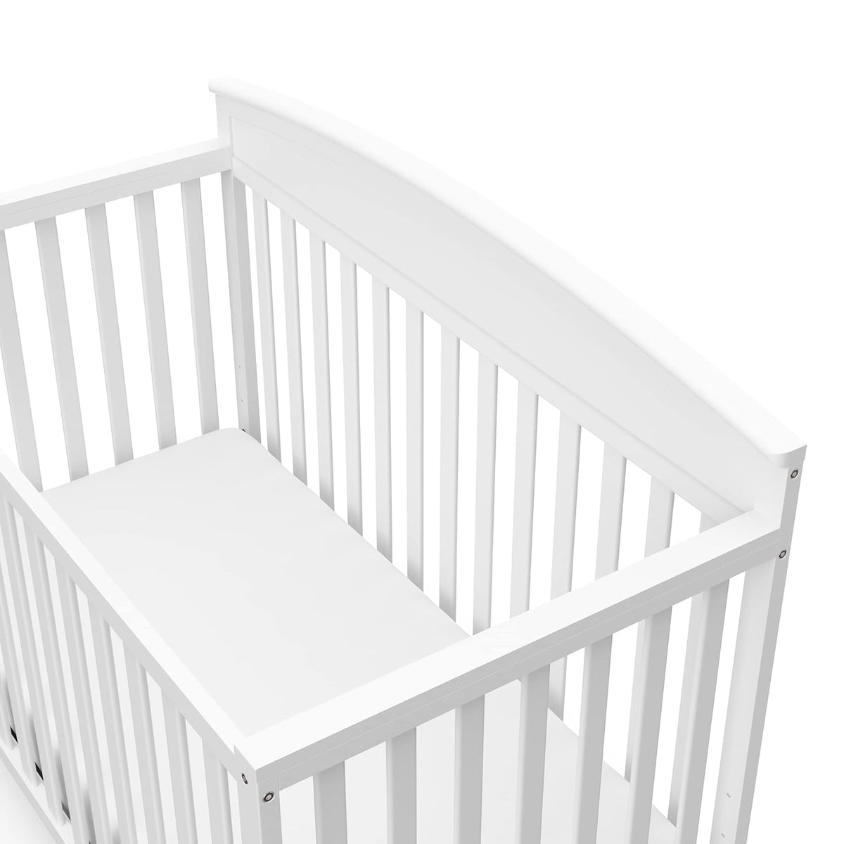 Close-up three-quarter view of a white crib corner showing vertical slats and a gently curved headboard.