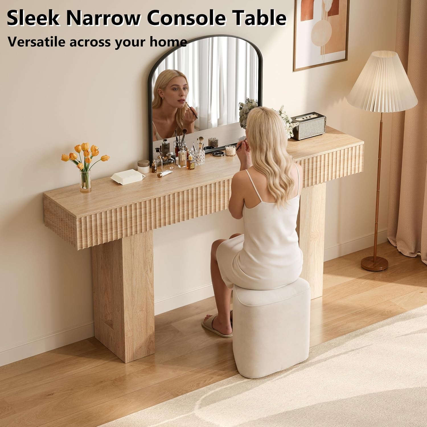 Narrow console table used as a vanity with a seated person at a mirror and decorative items on the top