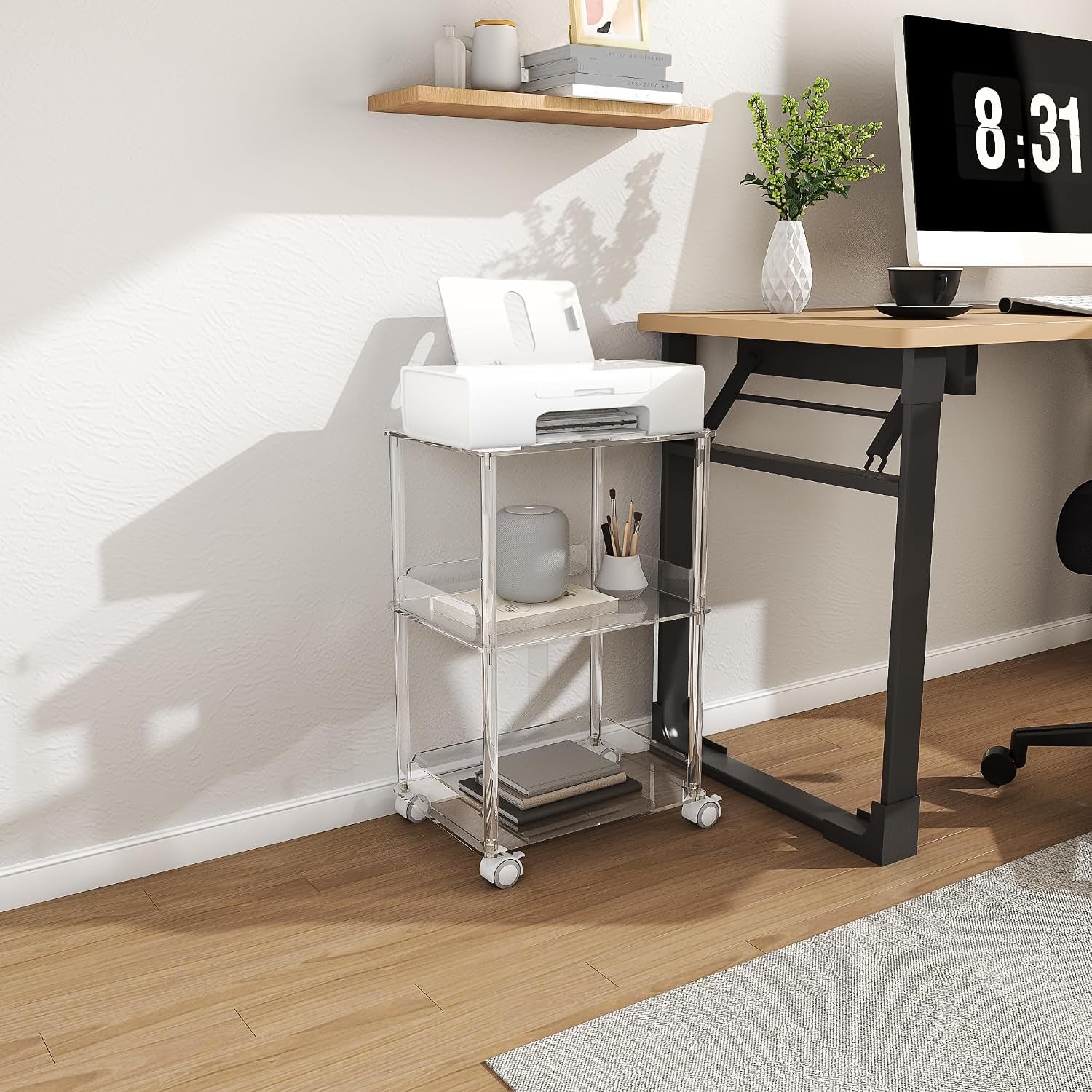 Side-angle view of clear acrylic three-tier stand in a home office next to a desk and a basket of magazines