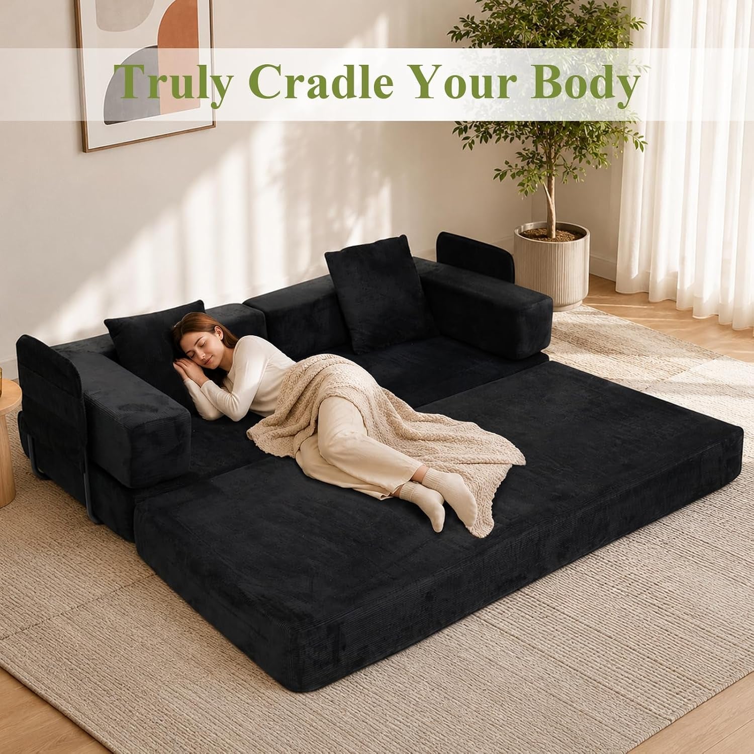 Top-down view of the sofa converted into a low bed with a woman lying under a blanket in a sunlit room.