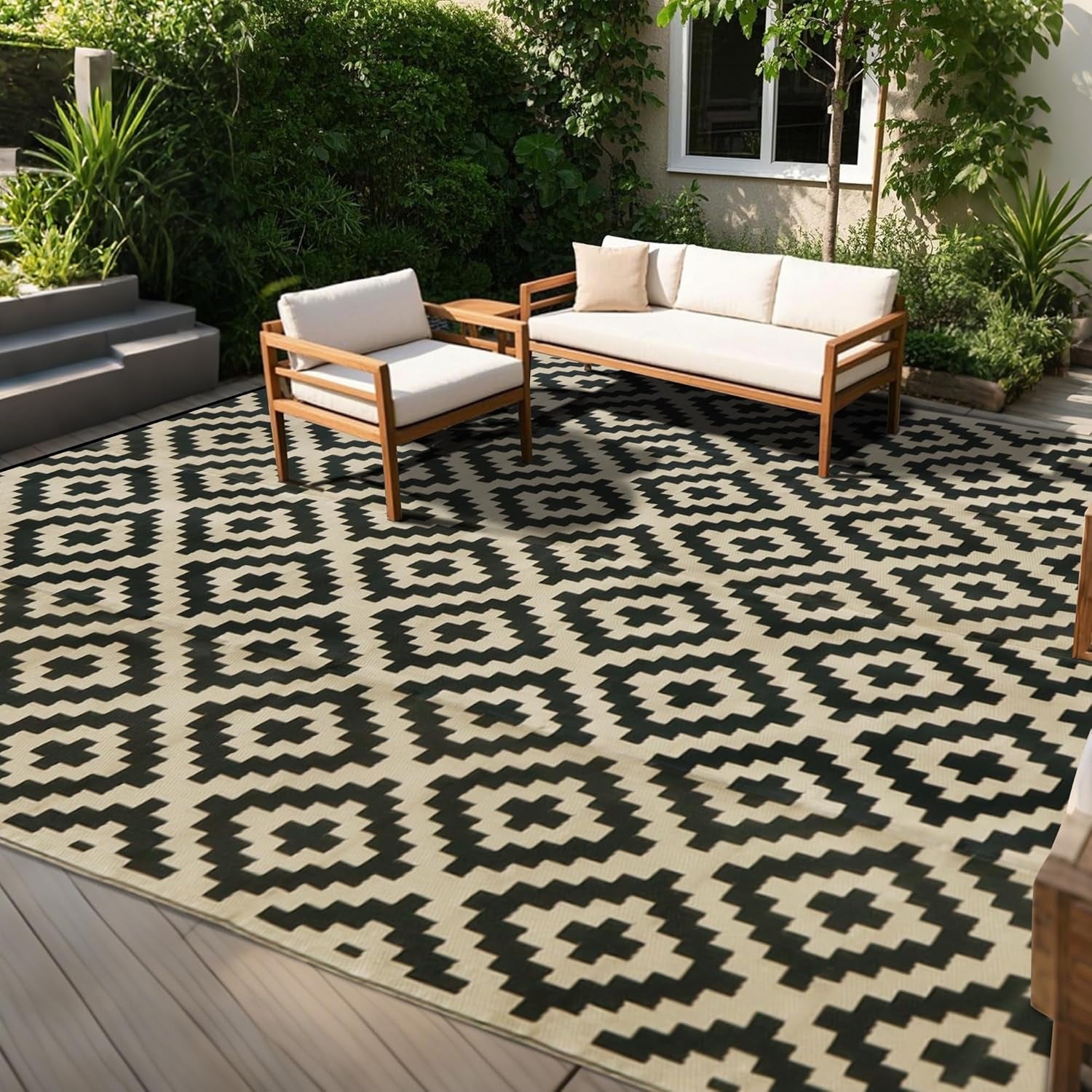 Wide deck view of a cream rug with bold black diamond pattern under a wooden sofa and chair.