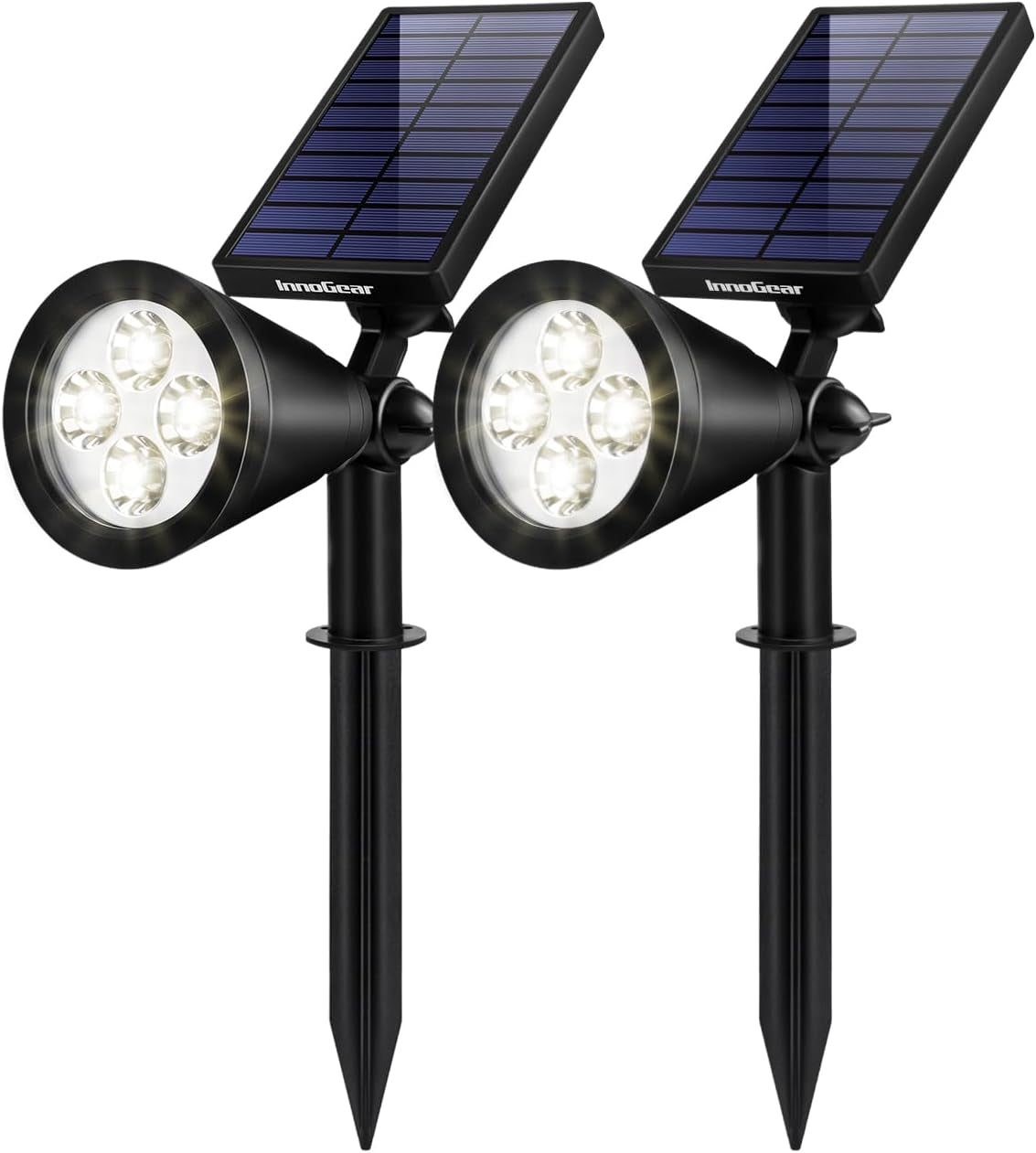 Close pair of black stake-mounted solar spotlights with warm white LEDs illuminated