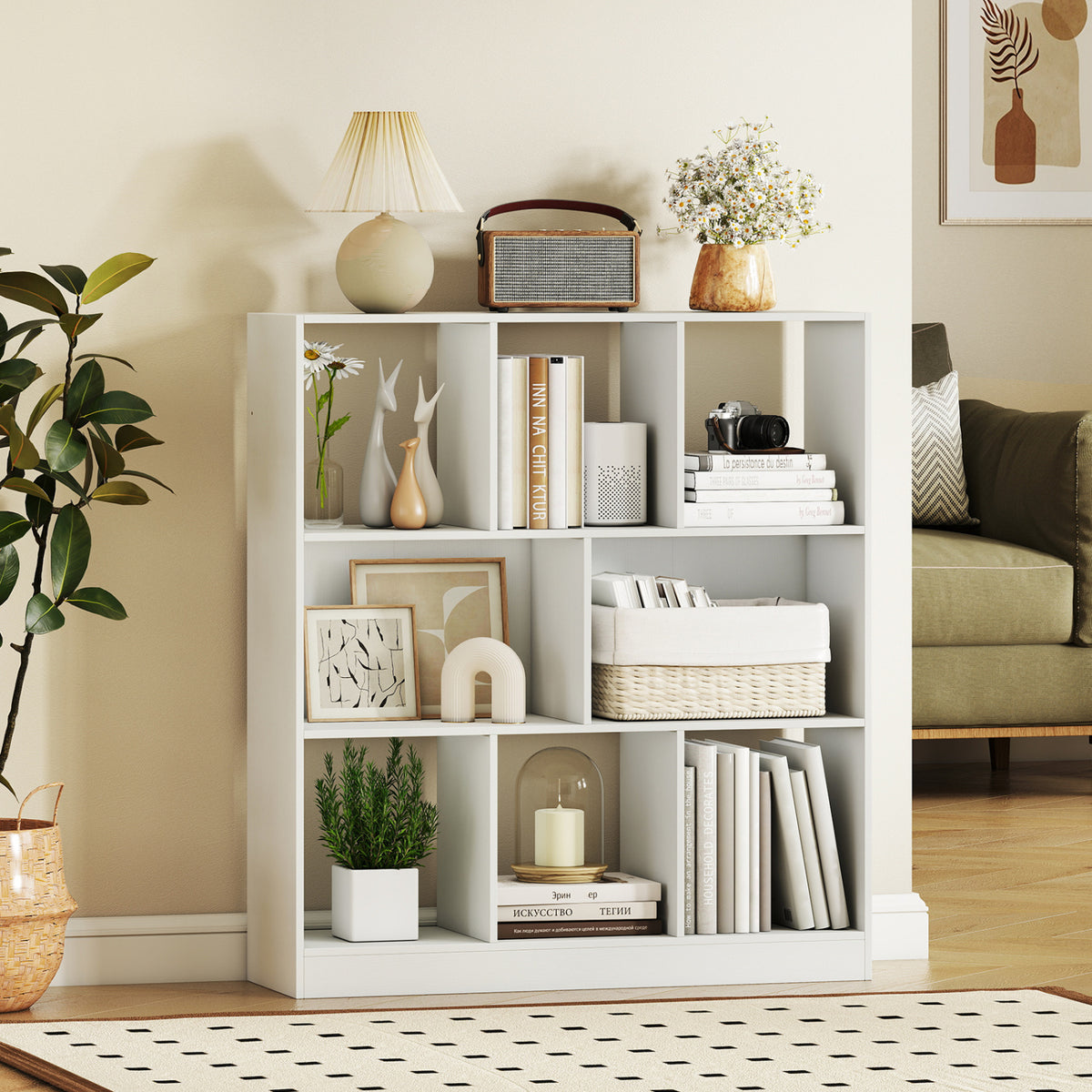 White compartment bookcase displayed beside a sofa, with books, framed art, and woven baskets.