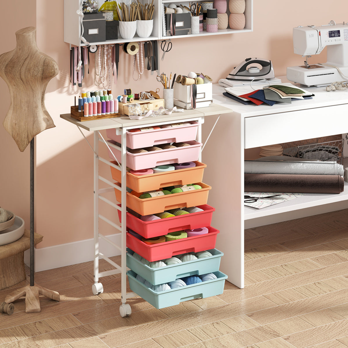 Rolling cart with pastel drawers beside a sewing table, surrounded by sewing supplies.