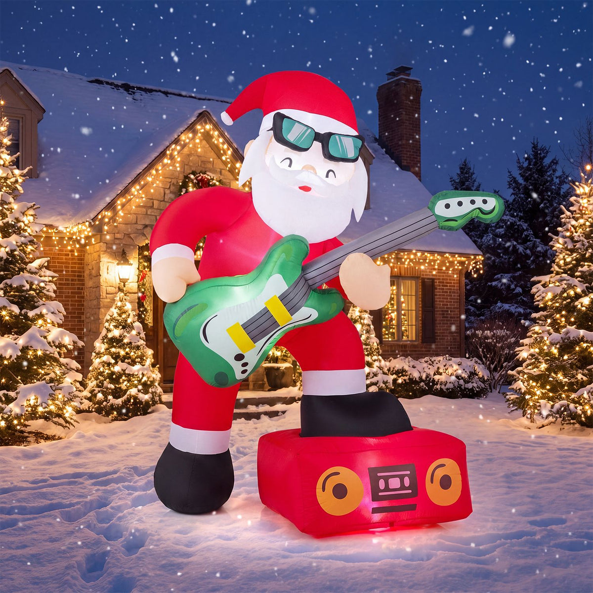 Santa with a green guitar stands in the snow before warmly lit homes and evergreen trees.