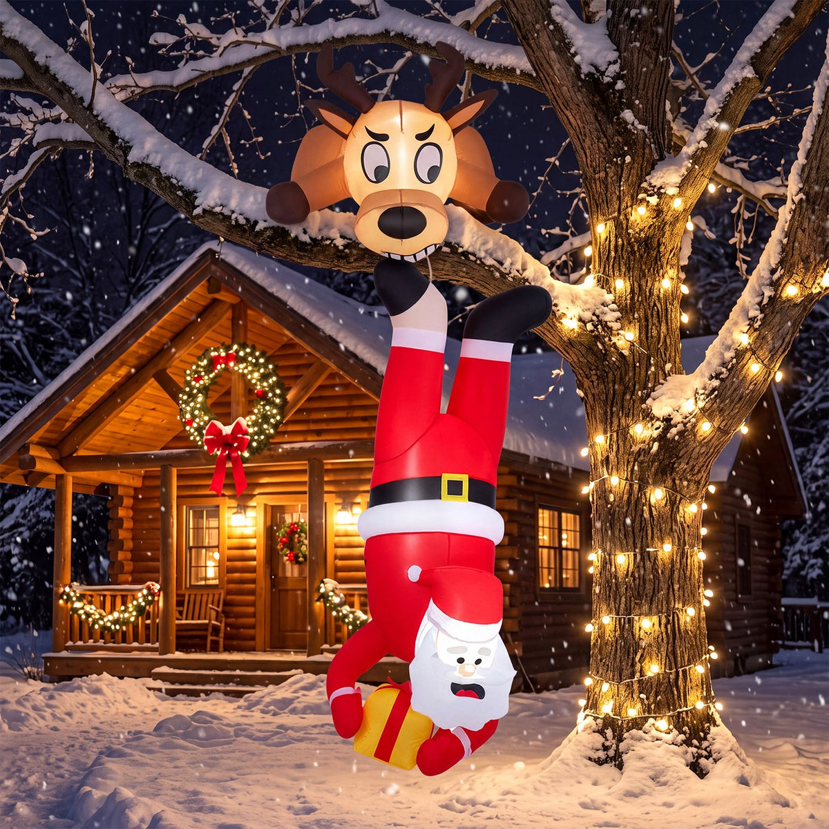 Inflatable Santa and reindeer hang upside down in a snowy yard beside a lit tree and cabin.