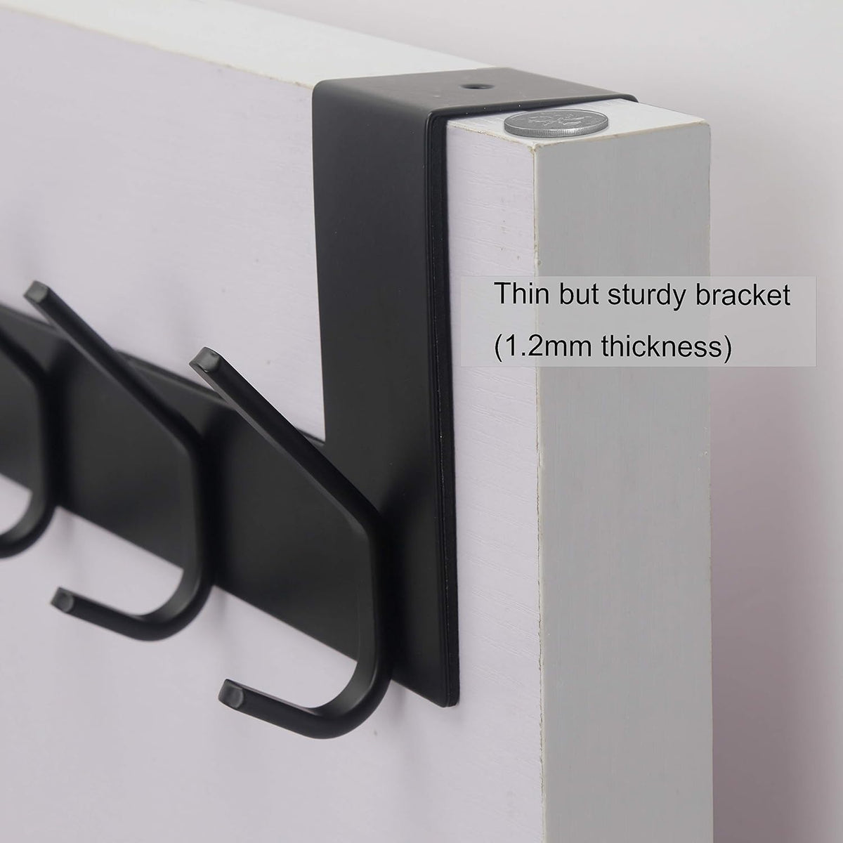 Close-up of black over-the-door bracket and two hooks on a white door edge