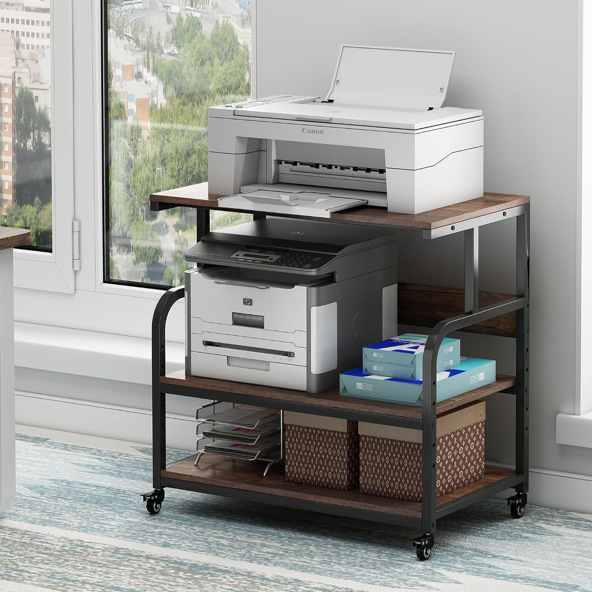 Black metal-framed three-tier stand with wood-tone shelves placed by a window holding printers and office supplies.