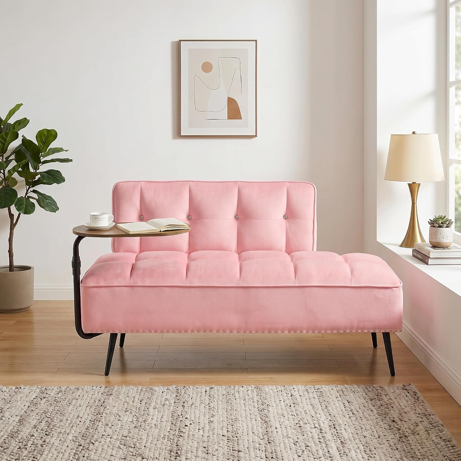 Pink velvet armless sofa chaise with button tufting and attached side table in a sunlit room.