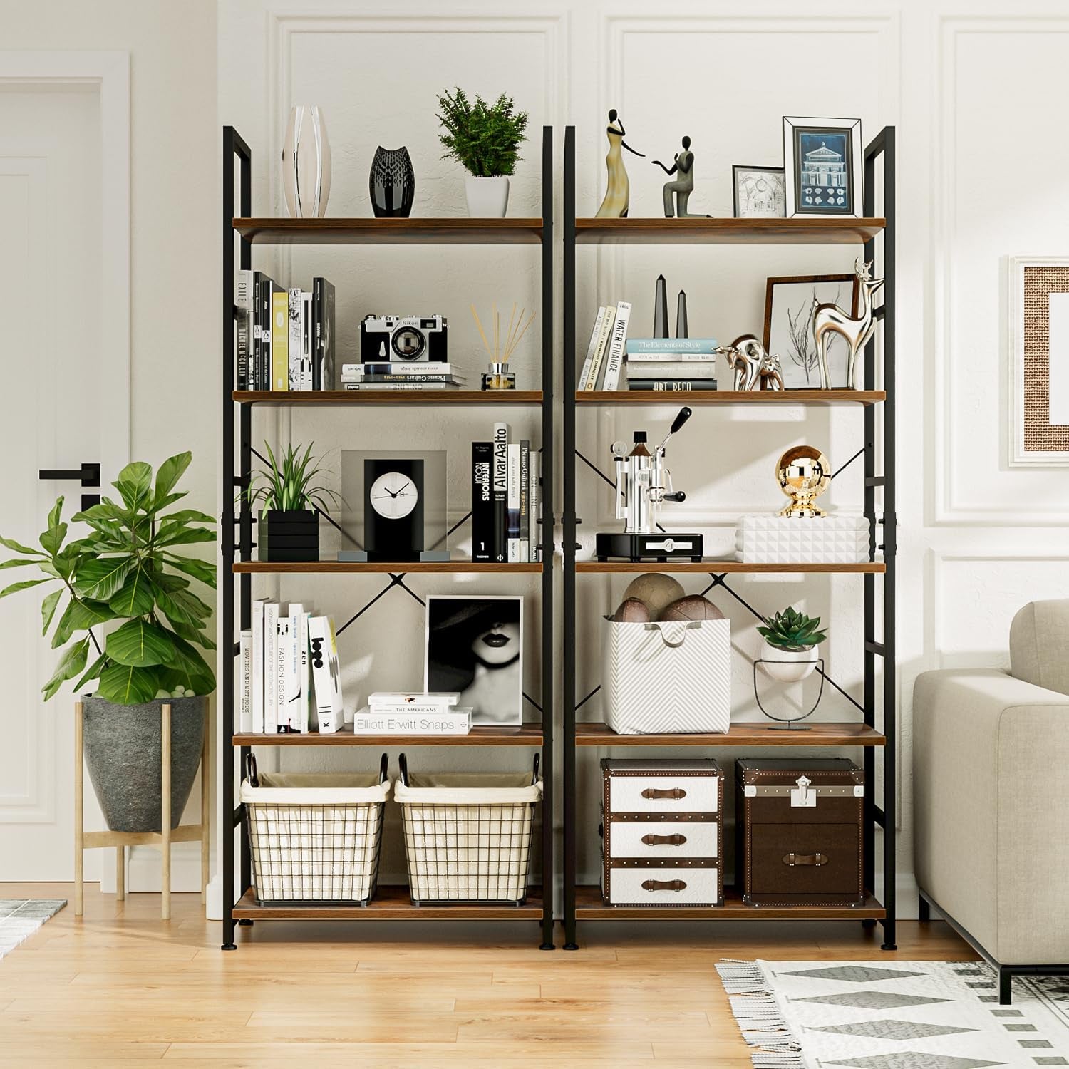 Two matching five-tier bookcases with black frames and wood-tone shelves styled in a living room with plants and sofa.