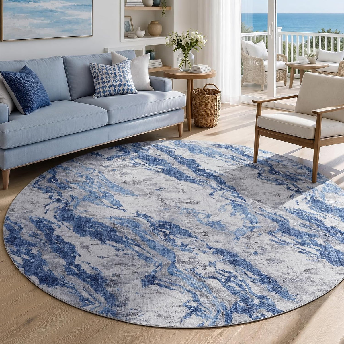 Round blue-and-white abstract rug in a living area, placed near a light-blue sofa and wooden side chair with coastal decor.