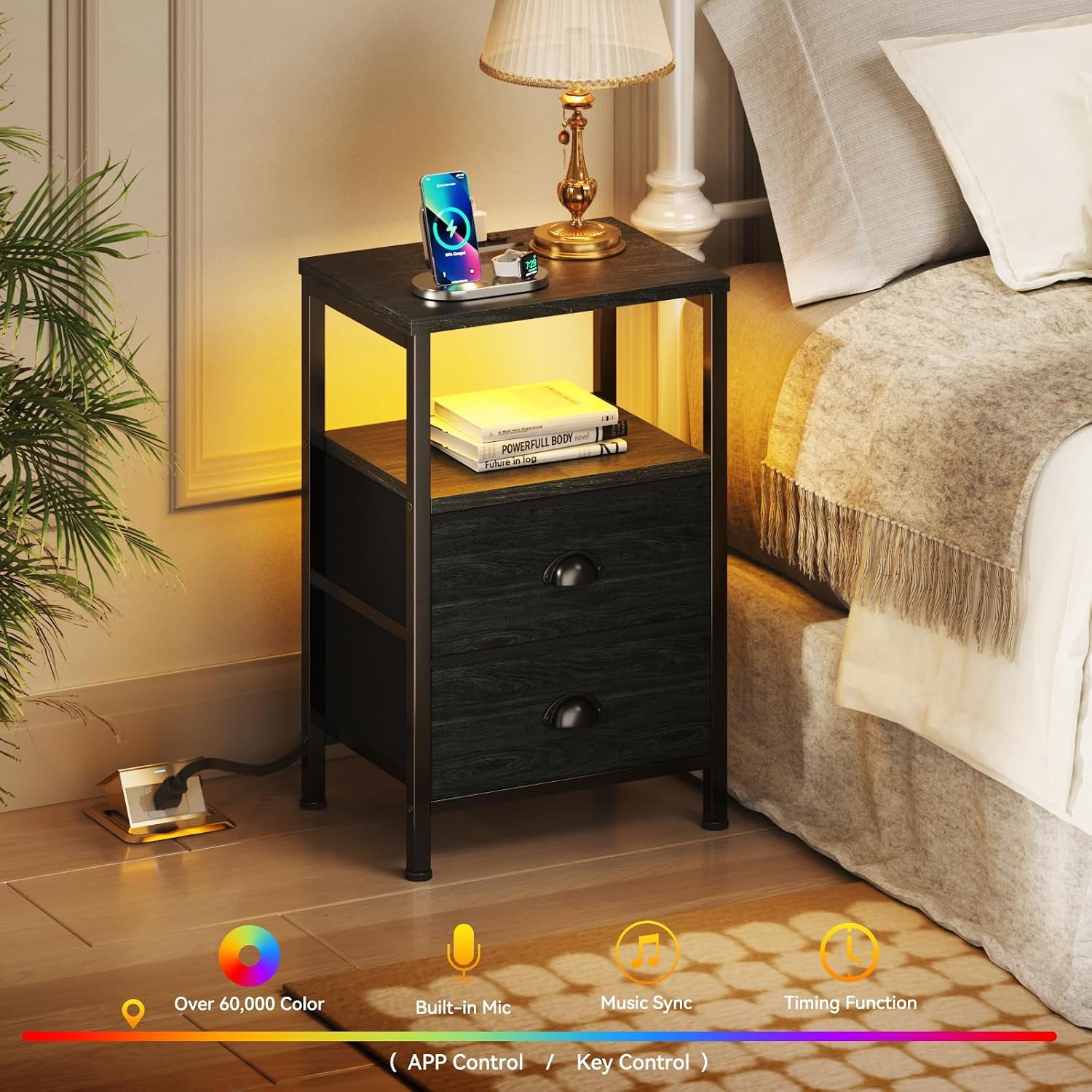 Black nightstand beside a bed with lamp on top, illuminated shelf, and charging station on the tabletop