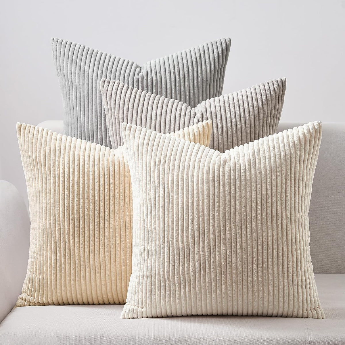 Five ribbed square pillows in neutral cream and light gray tones on a sofa