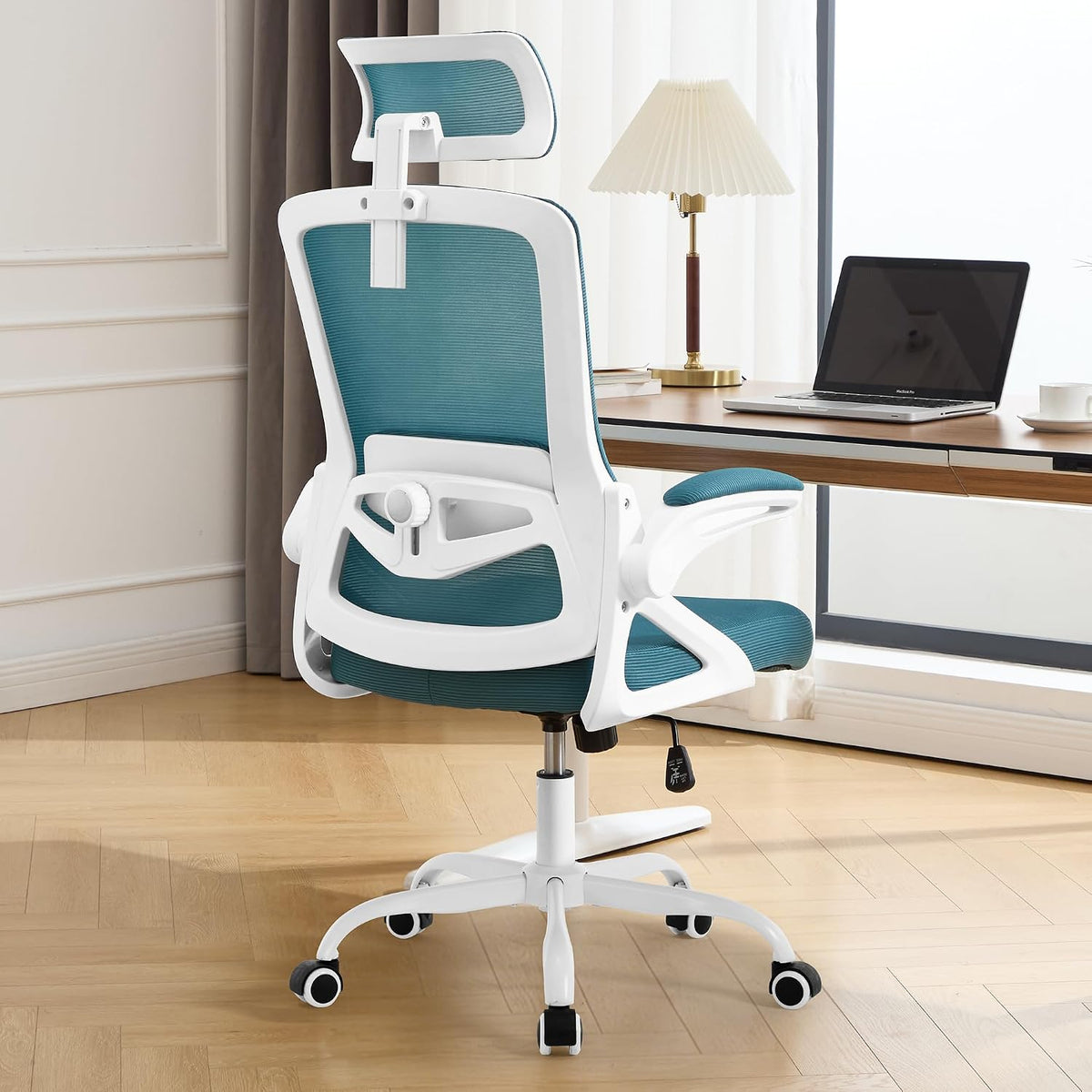 Rear view of a teal mesh chair with white frame positioned at a desk and lamp.