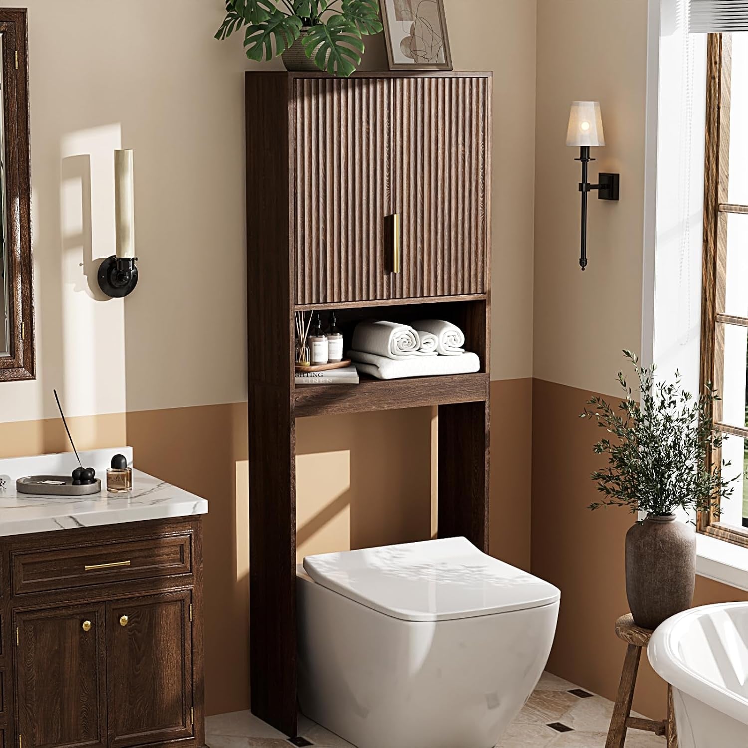 Dark walnut over-the-toilet storage cabinet with fluted doors and brushed-gold handle, angled front view in a staged bathroom