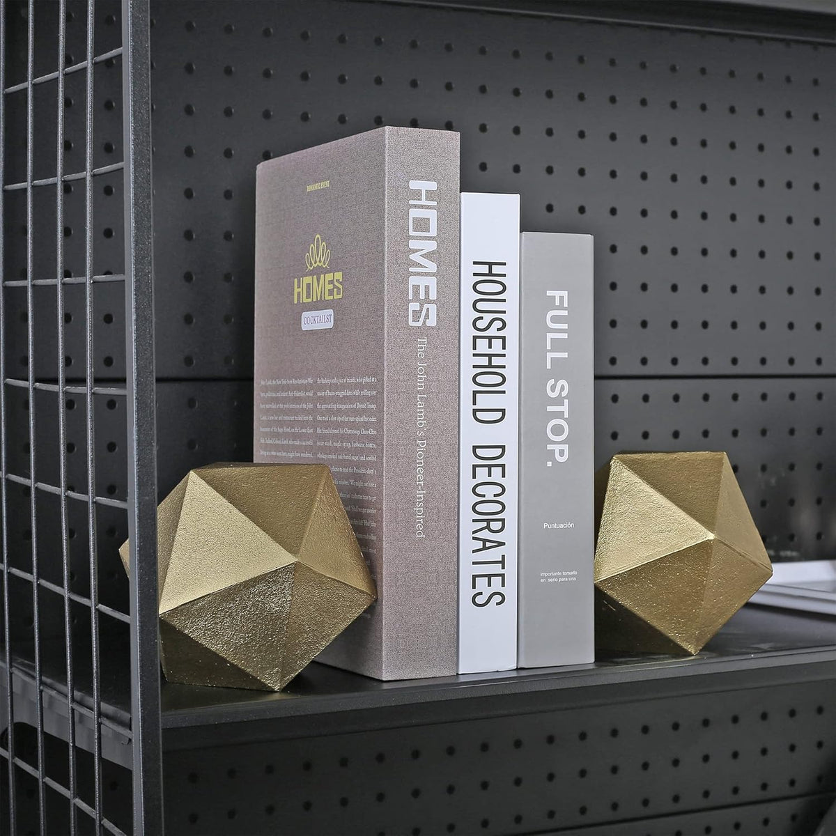 Pair of gold geometric bookends holding books on a black metal shelf, side view inside a shelving unit