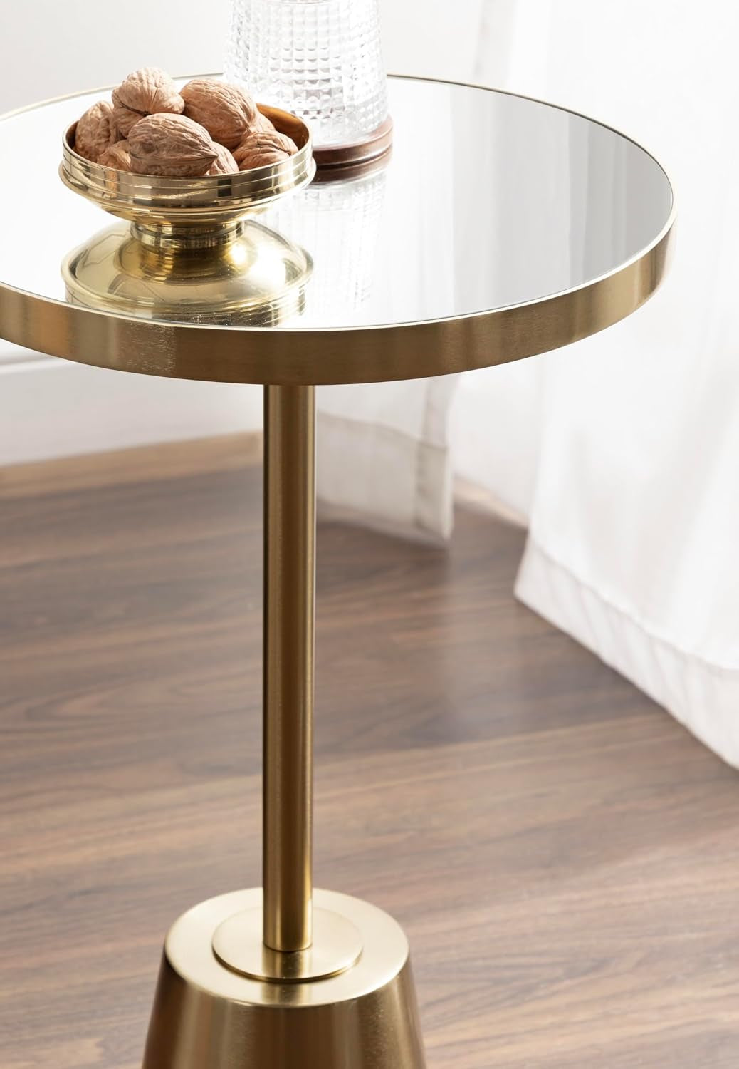 Close-up of the mirrored tabletop and gold rim with a small decorative bowl and glass on top