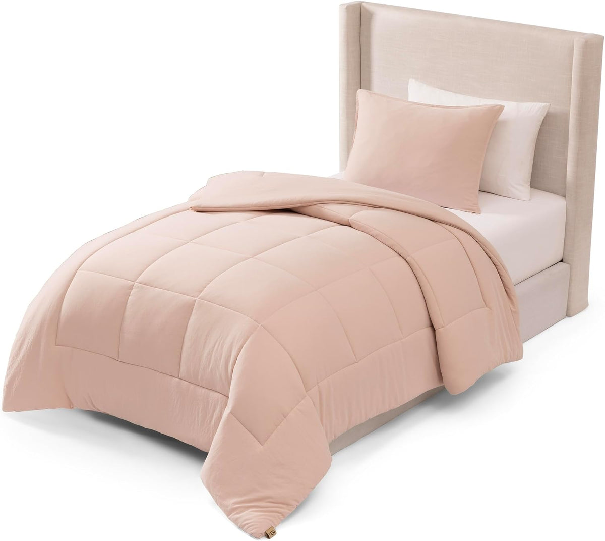 Single bed styled with a pale blush comforter turned down at the top and one sham propped against the headboard