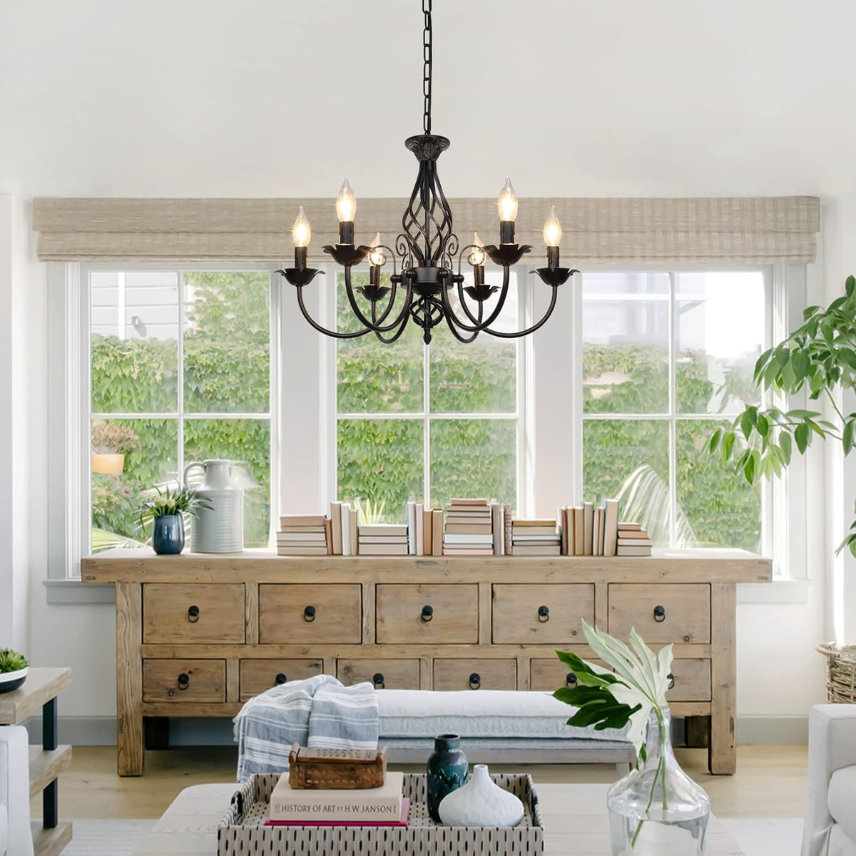 Matte black six-light chandelier hung over a console table in a bright living room