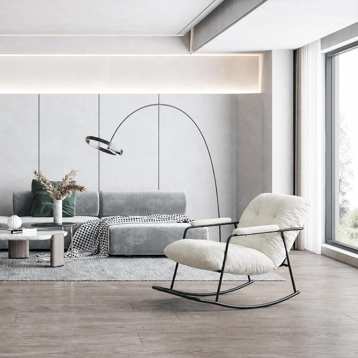 White boucle rocking chair with black metal frame placed on wood floor in a bright living room by a gray sofa and tall