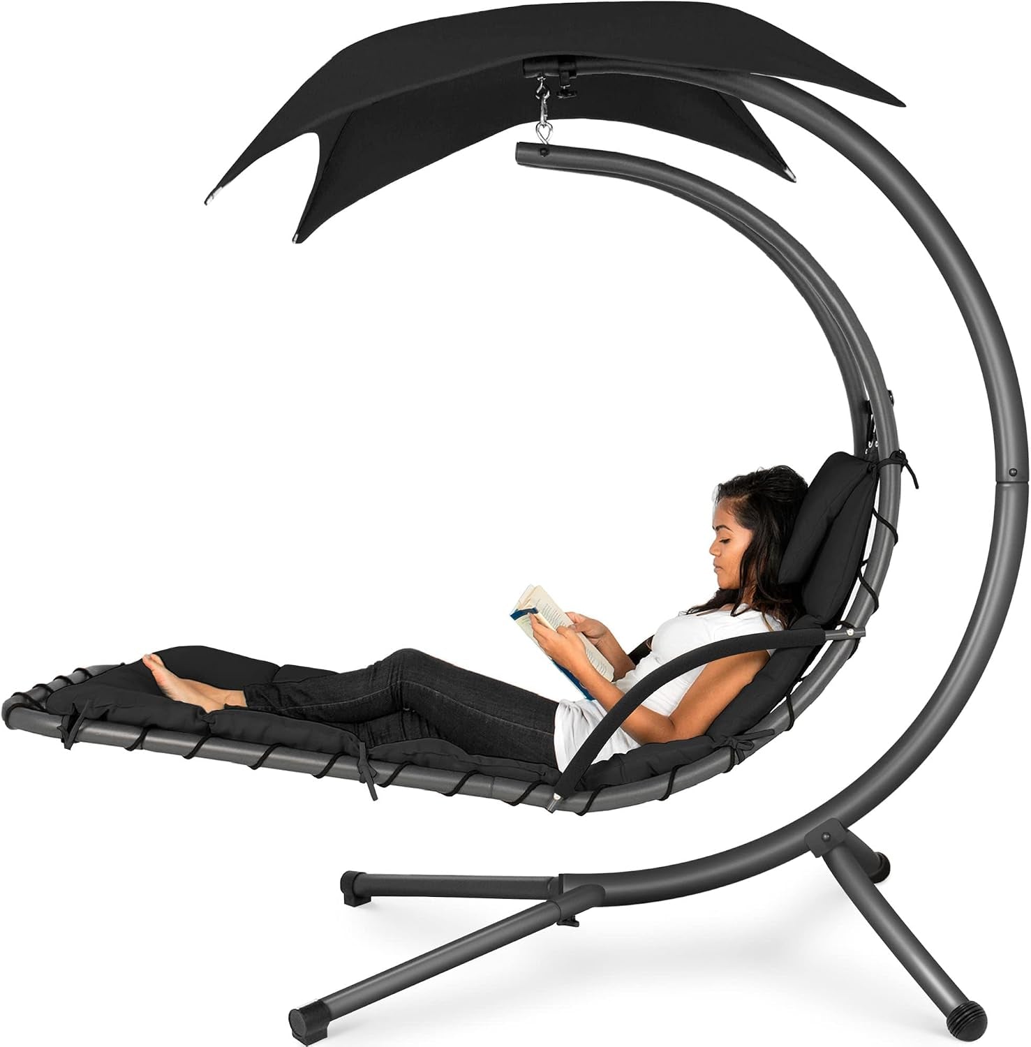 Curved hanging chaise lounge with dark charcoal cushion and canopy, woman reclining and reading.