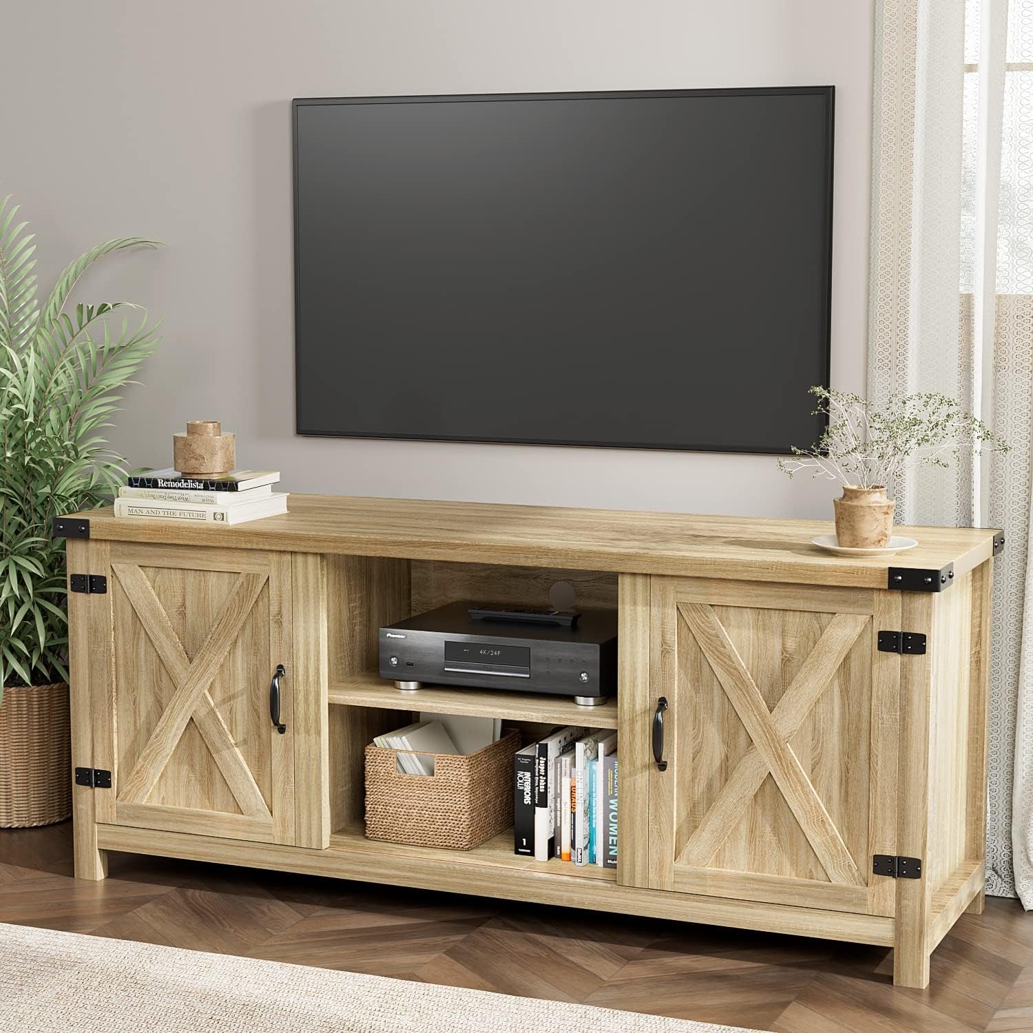 Light wood TV stand with X-paneled doors, media components and books on the open center shelves