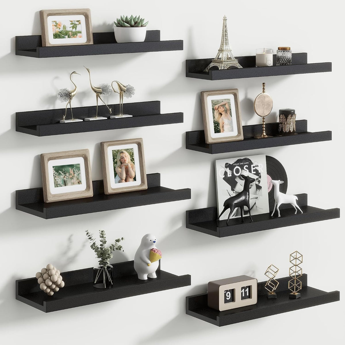 Close view of staggered black floating picture ledges holding frames and small sculptures