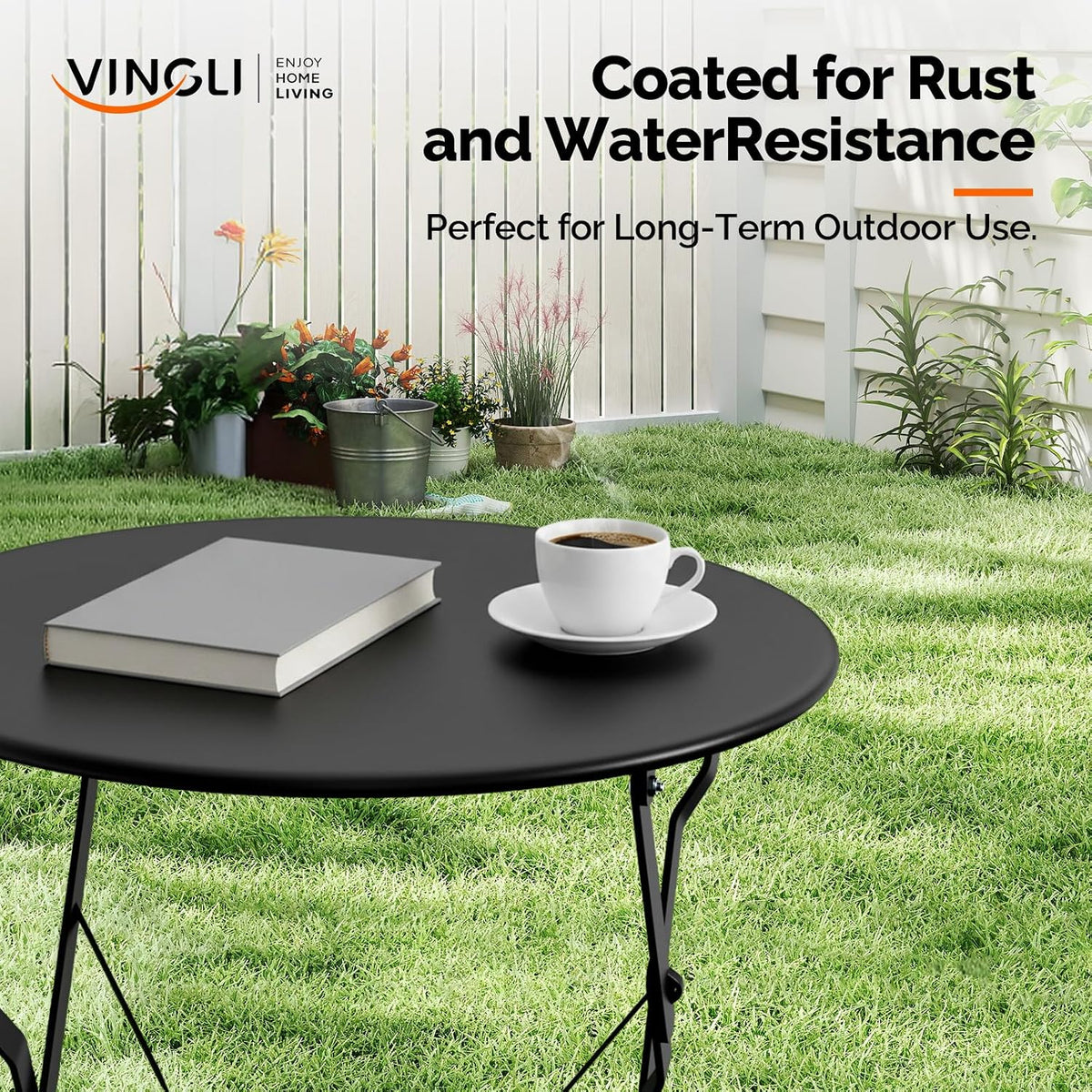 Close-up of the black round table top with a coffee cup and book on a grassy outdoor background