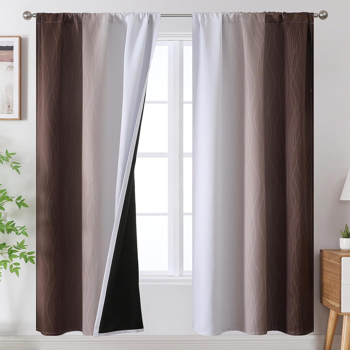 Window with two brown-to-white ombre curtains hung on a rod, one pulled back showing white face and black blackout lining.