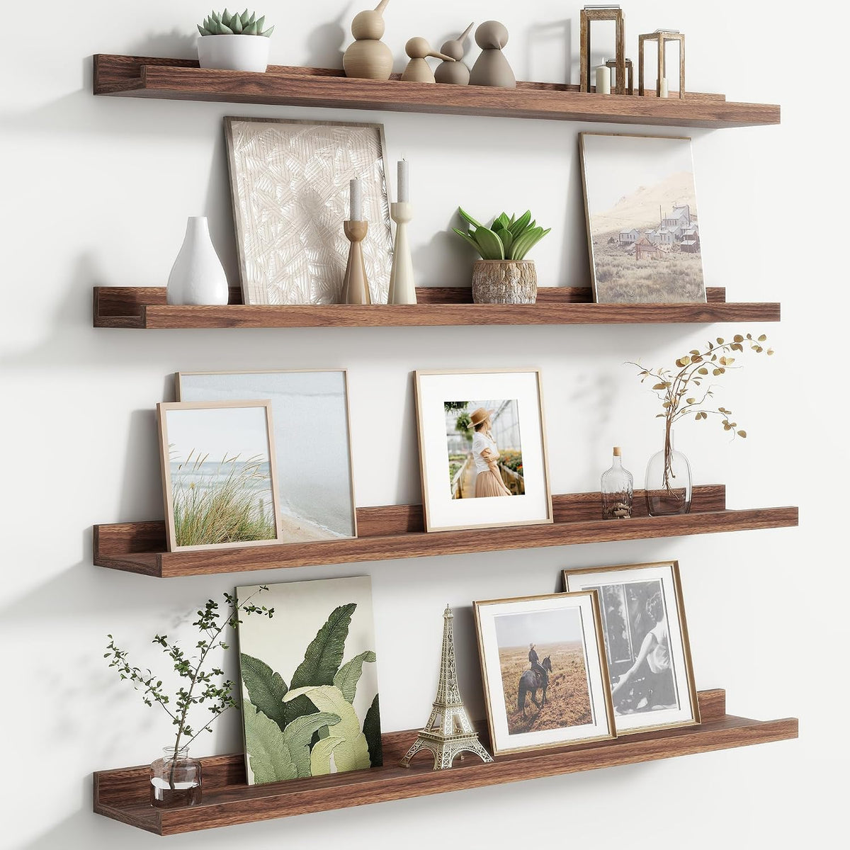 Close angled view of three dark wood picture ledges styled with framed prints, plants and a small Eiffel Tower.