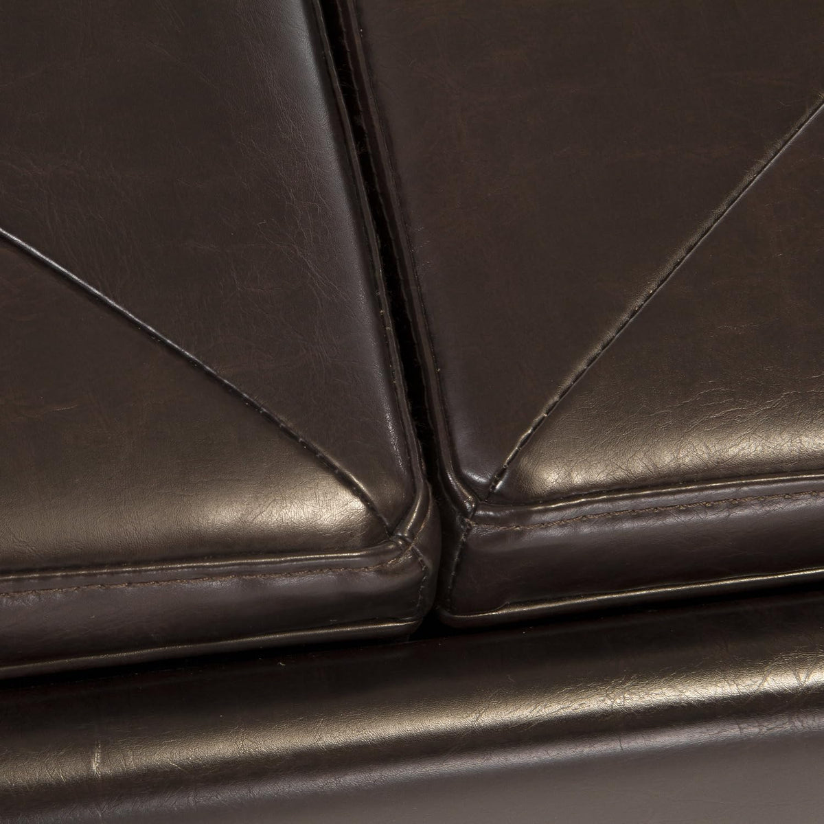 Close-up of the join between two brown bonded leather seat cushions showing seams and piping detail