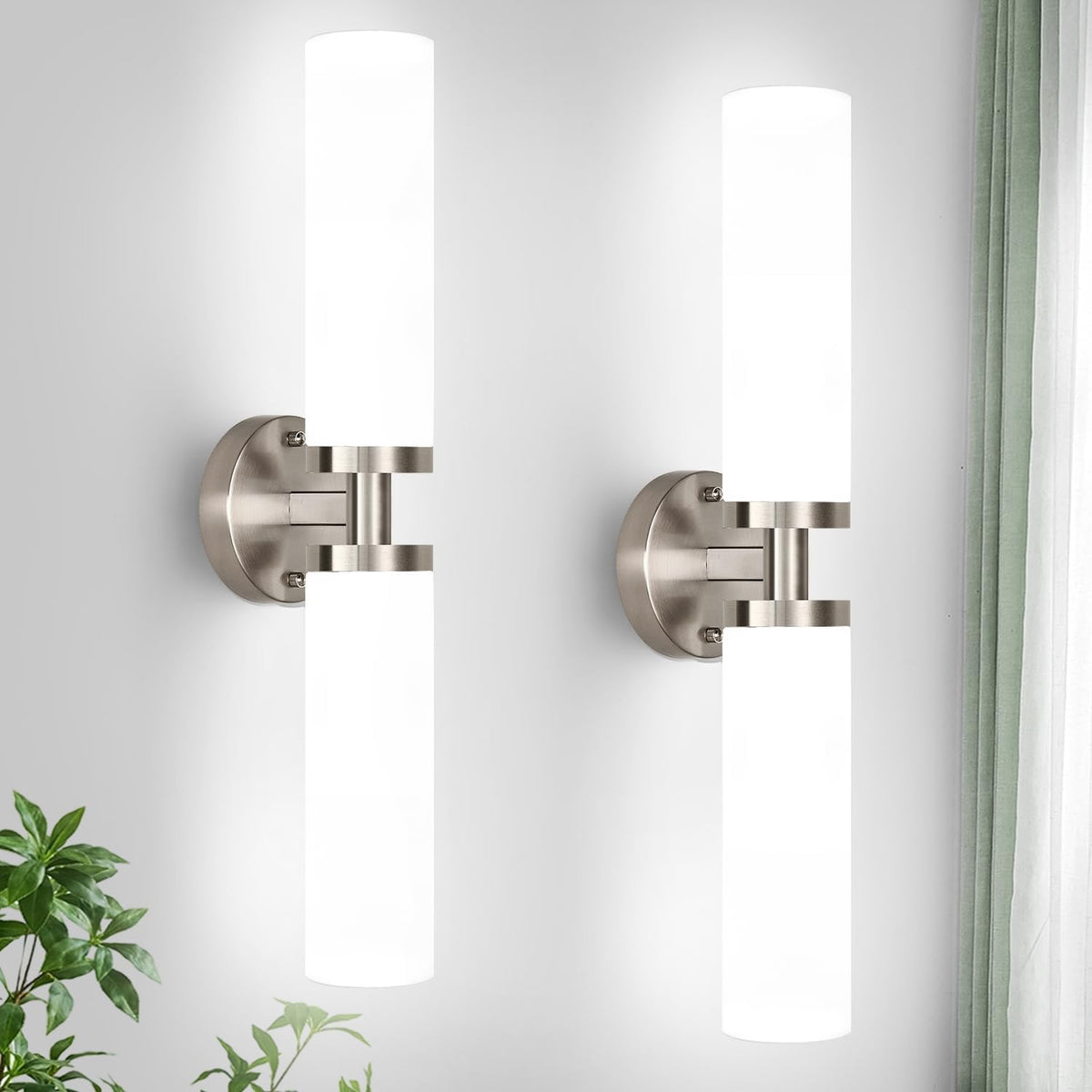 Pair of brushed nickel wall sconces with frosted white cylindrical shades lit brightly on a pale wall.