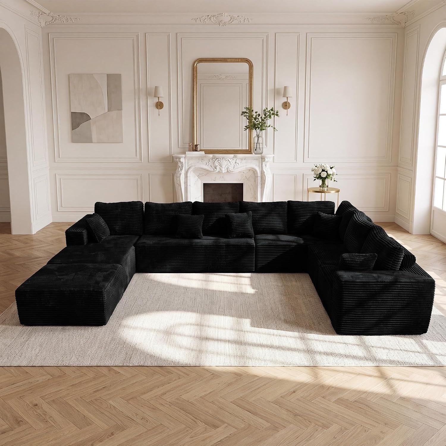 Large black L-shaped modular sectional with chaise arranged U-shape on a light rug in a bright, classic living room.