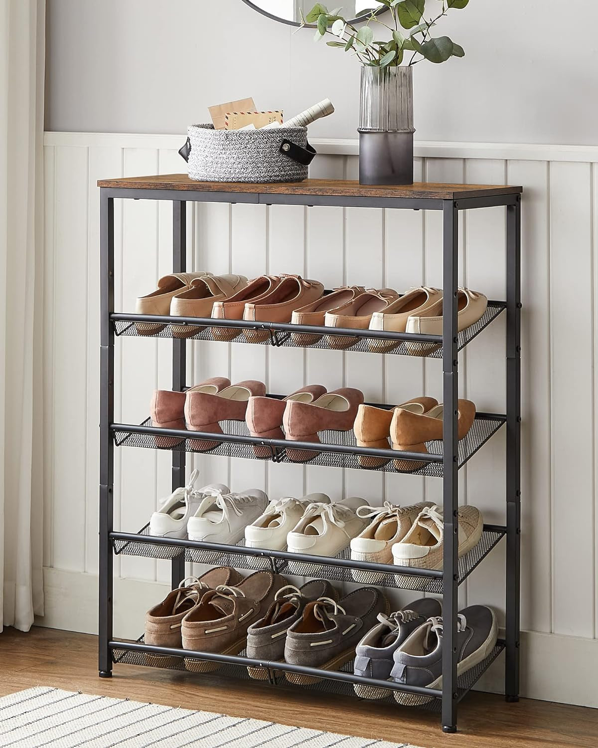 Front view of a filled five-tier mesh shoe organizer with shoes on each shelf and decorative items on the top.