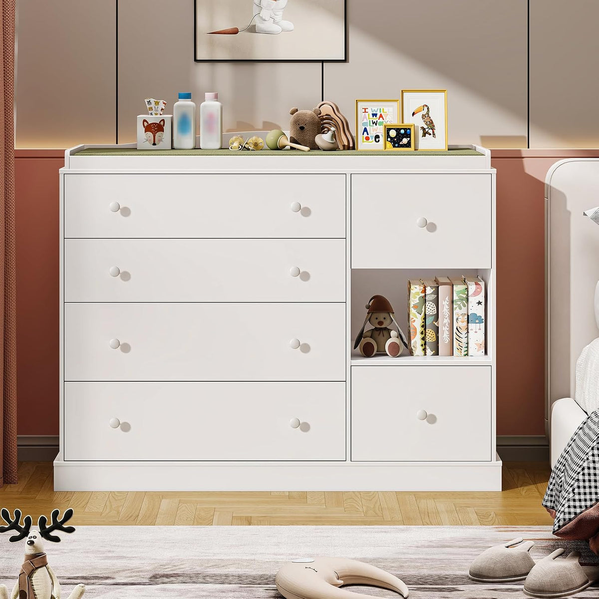 Front view of the white dresser showing drawers, open cubby with books and a toy, and decor on top.