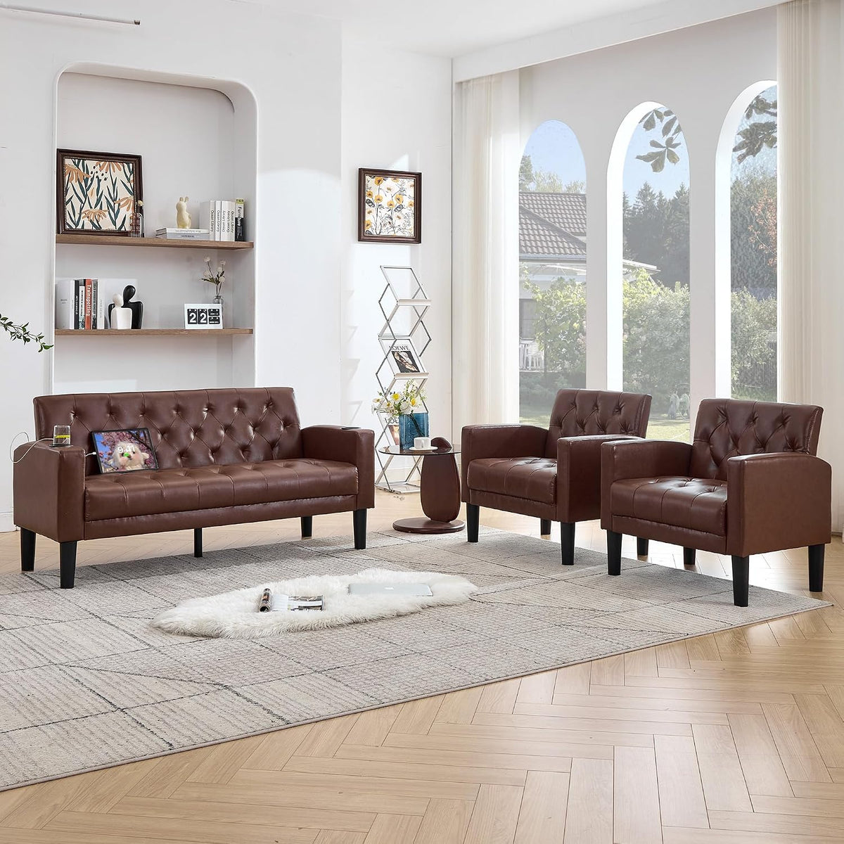 Brown tufted loveseat and two armchairs in a bright room with tall arched windows behind