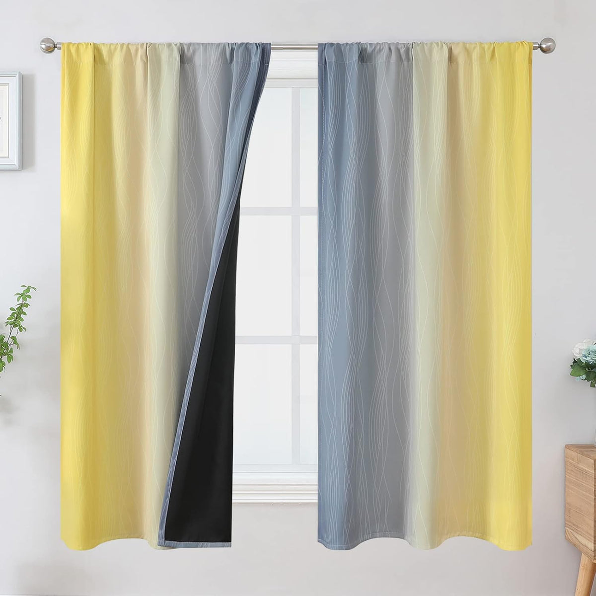 Window hung with yellow-to-gray ombre curtains patterned with thin wavy lines and showing a black blackout backing on one