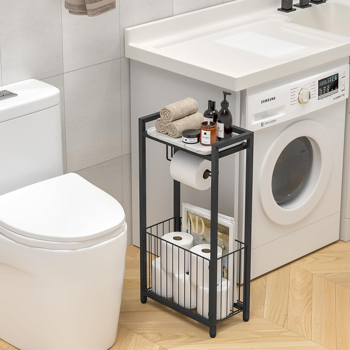 Black toilet paper holder placed between toilet and washing machine with top shelf styled with towels and candles