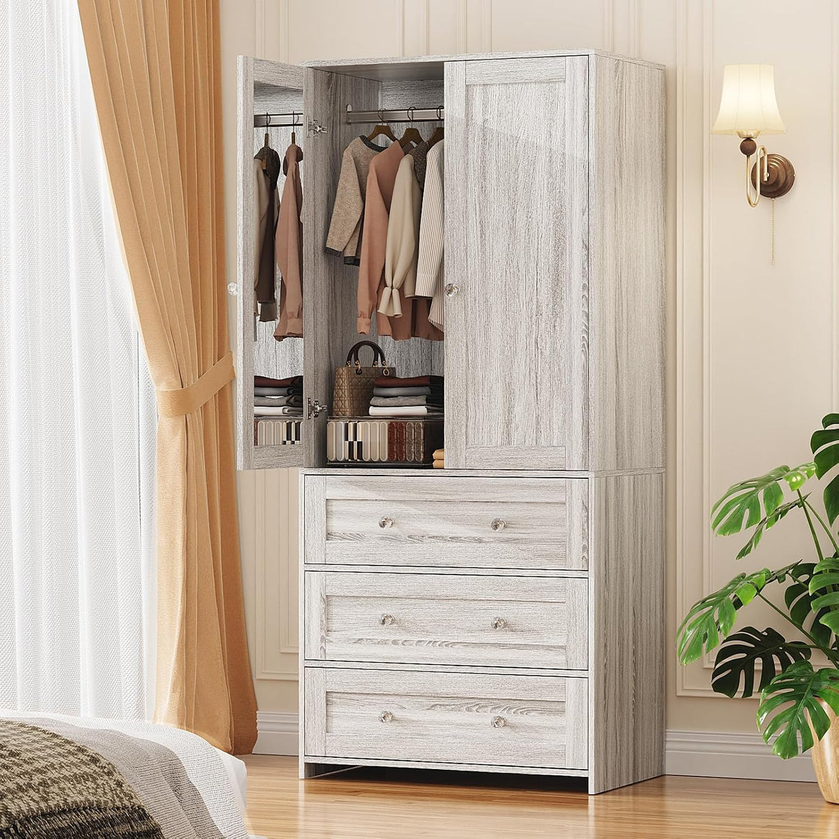 Light gray/whitewashed tall wardrobe with three lower drawers and upper cabinet, left door open showing hanging garments and