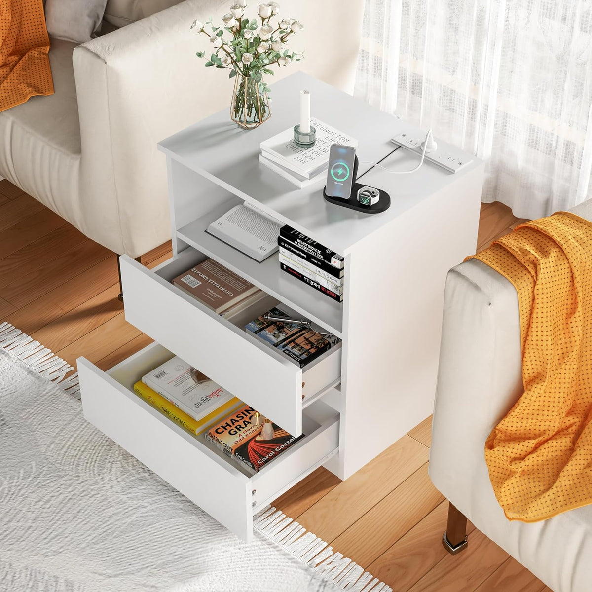 Top-down view of a white nightstand with two open drawers, books and charger on top