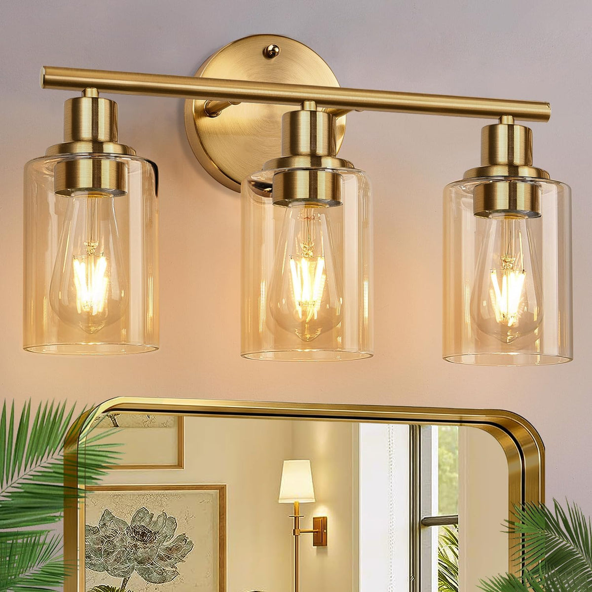 Close crop of a three-bulb brass-finish wall light with clear glass shades above a mirror