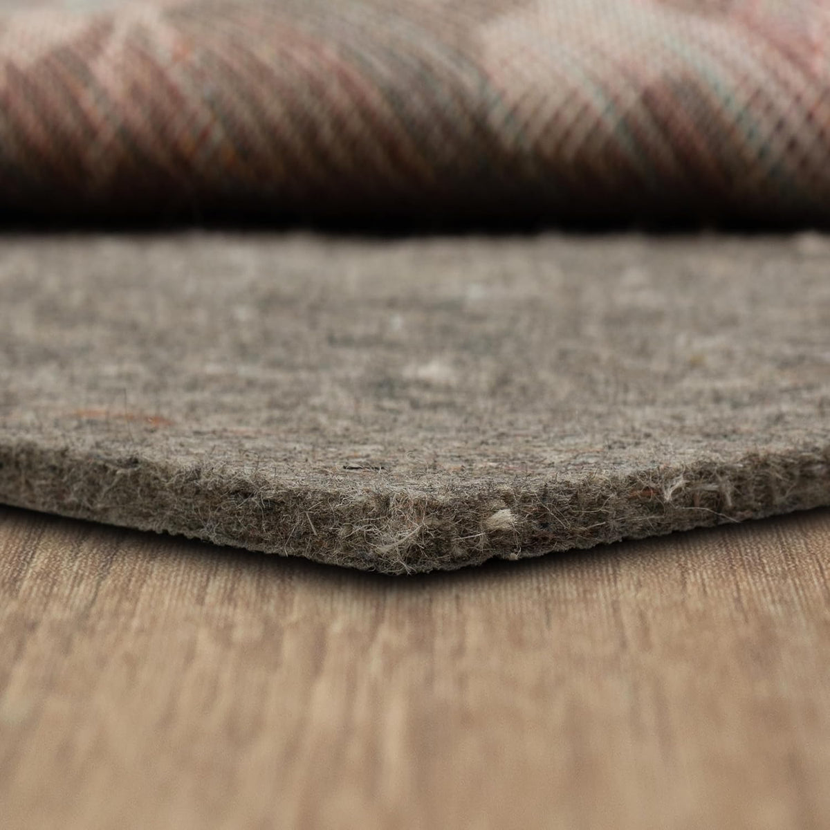 Frontal close-up of the felt pad edge lying flat, highlighting textured surface and stray fiber tufts.