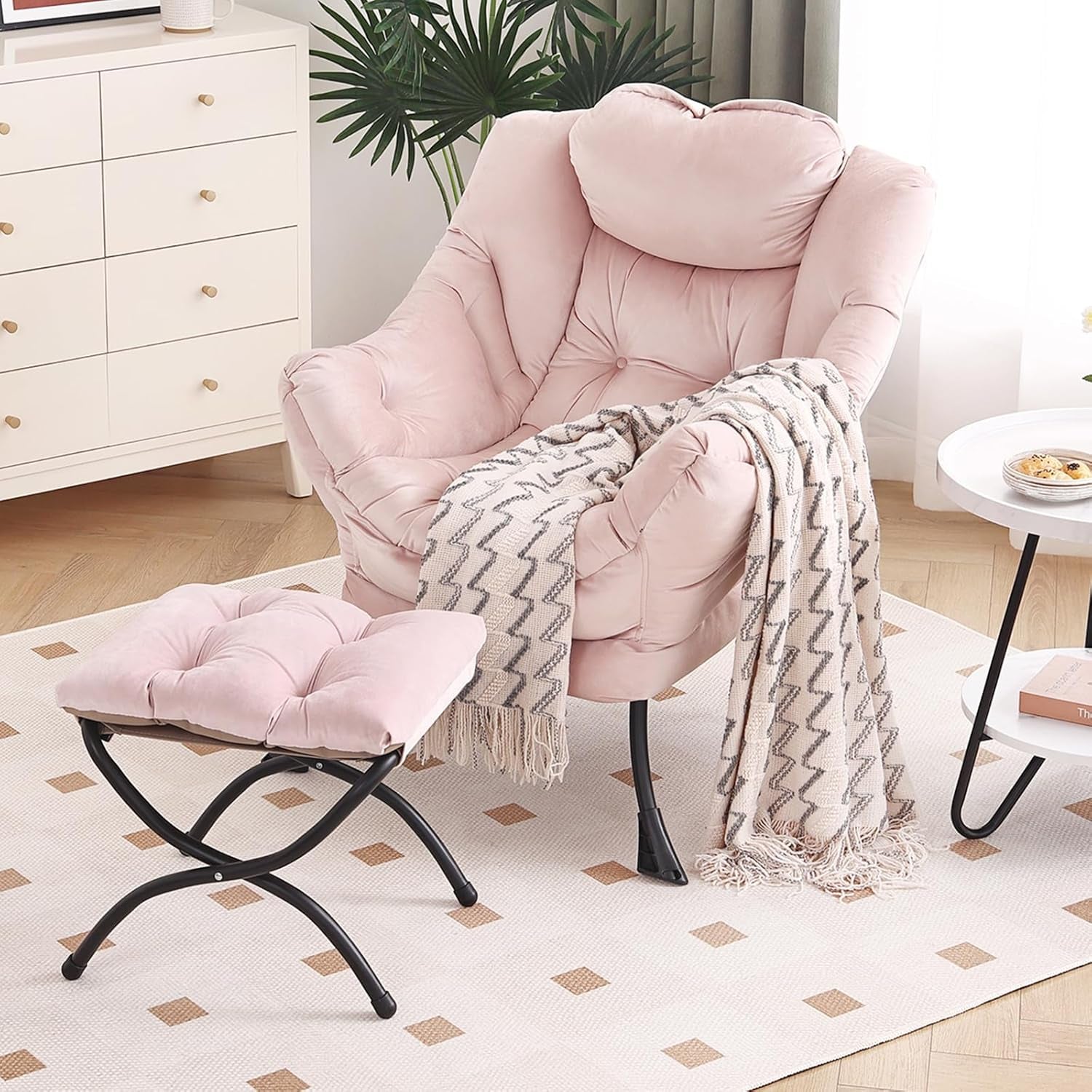 Pink cushioned lounge chair with matching ottoman in a bright room, patterned throw draped over arm.