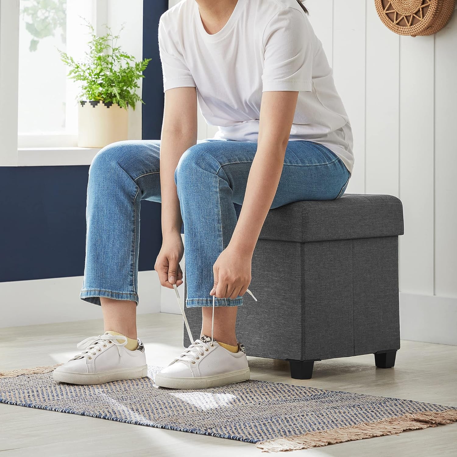 Person seated on the ottoman tying shoes, side view demonstrating seating use