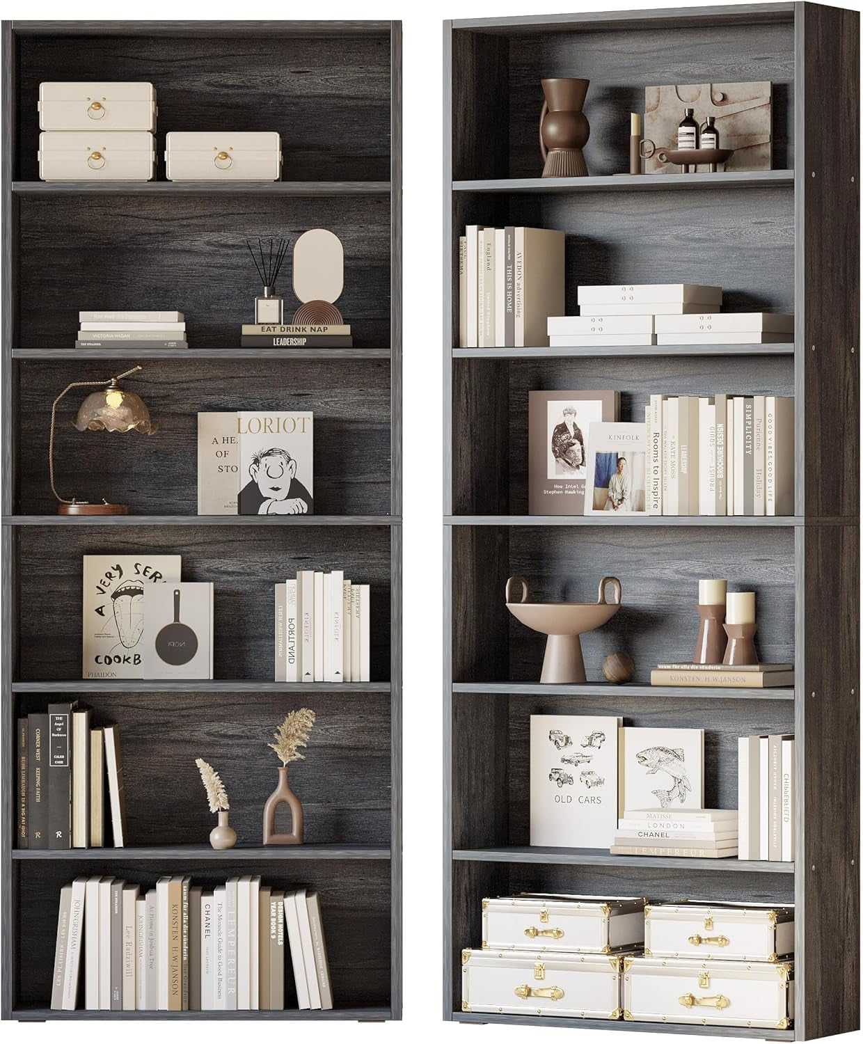 Pair of gray wood bookcases filled with neutral decor, stacked white storage trunks and layered books