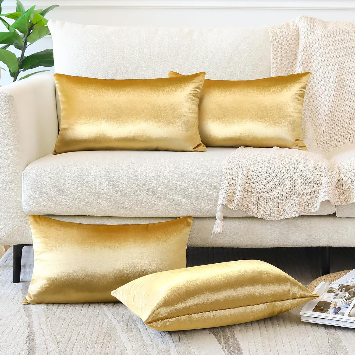 Gold rectangular and square velvet pillow covers displayed on a cream sofa with a textured throw.