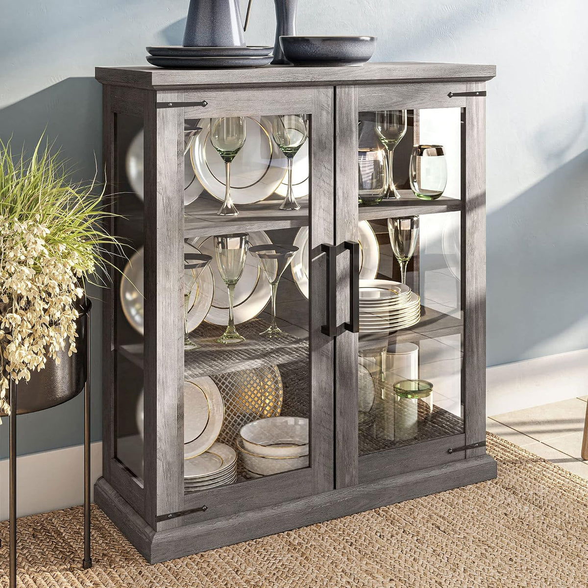 Short glass-front cabinet styled with dishes and glassware, close-up of doors and handles
