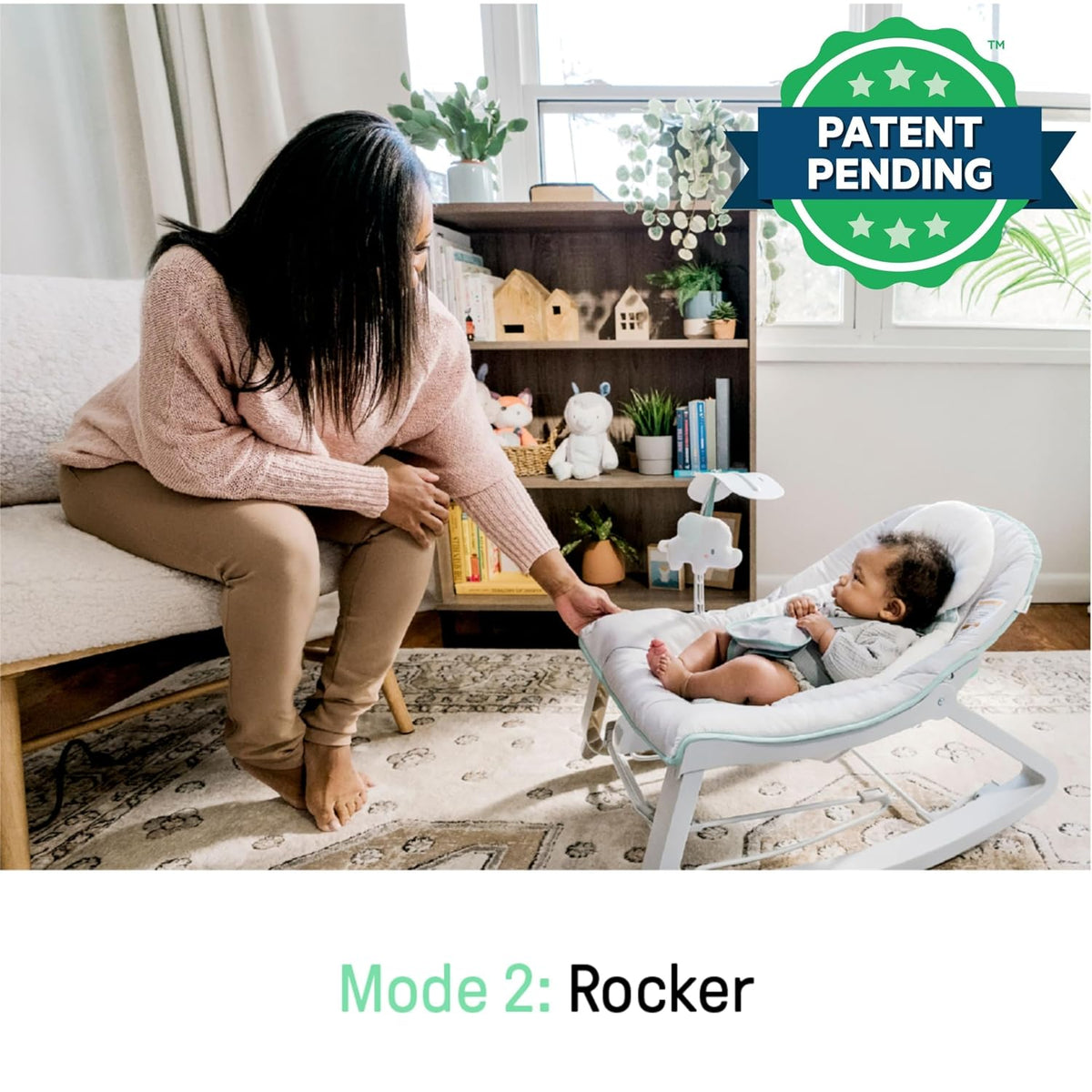Caregiver sitting on a sofa reaching toward a baby lying in the rocker in a bright living room