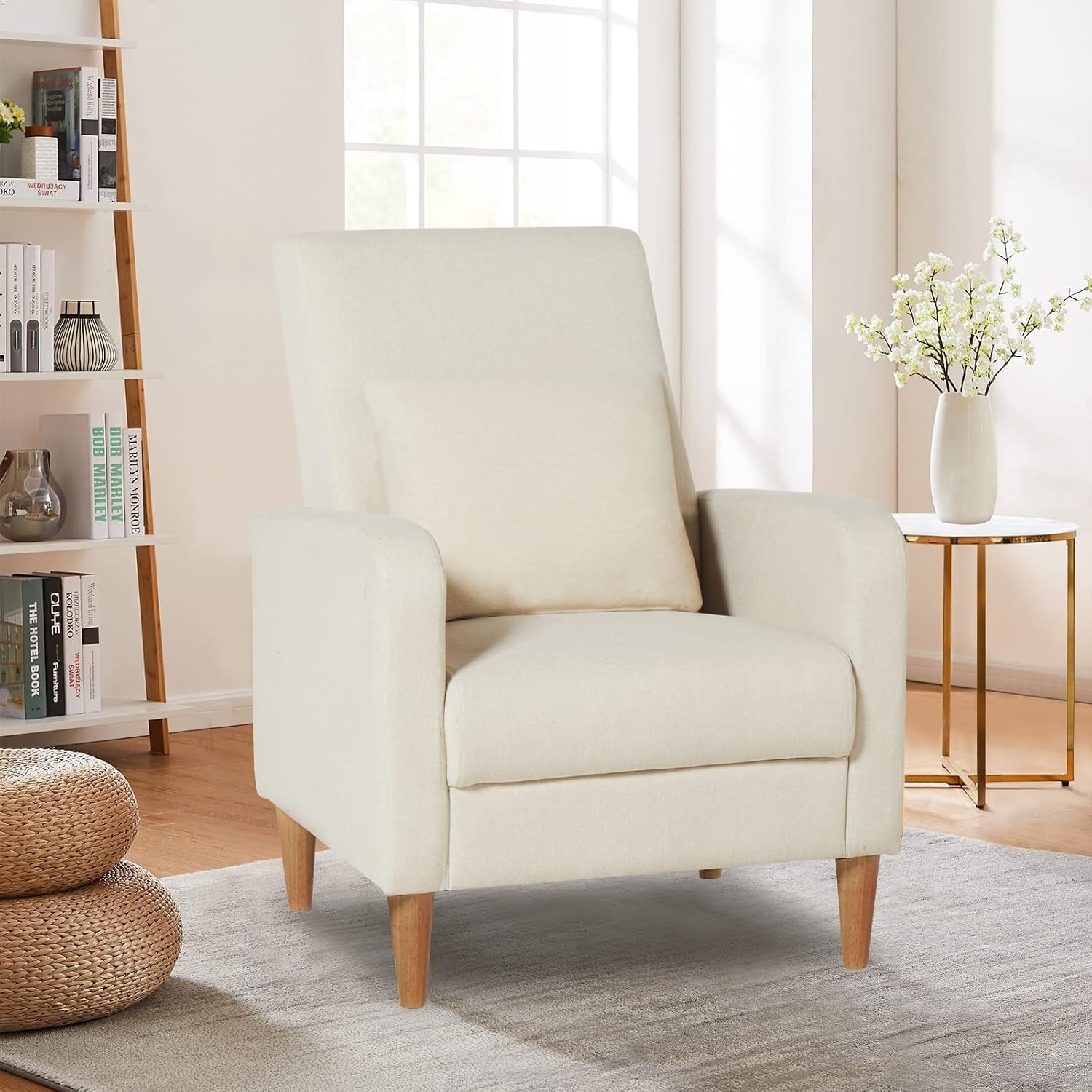 Cream high-back accent chair with removable pillow set in a bright living room beside a side table and bookshelf.