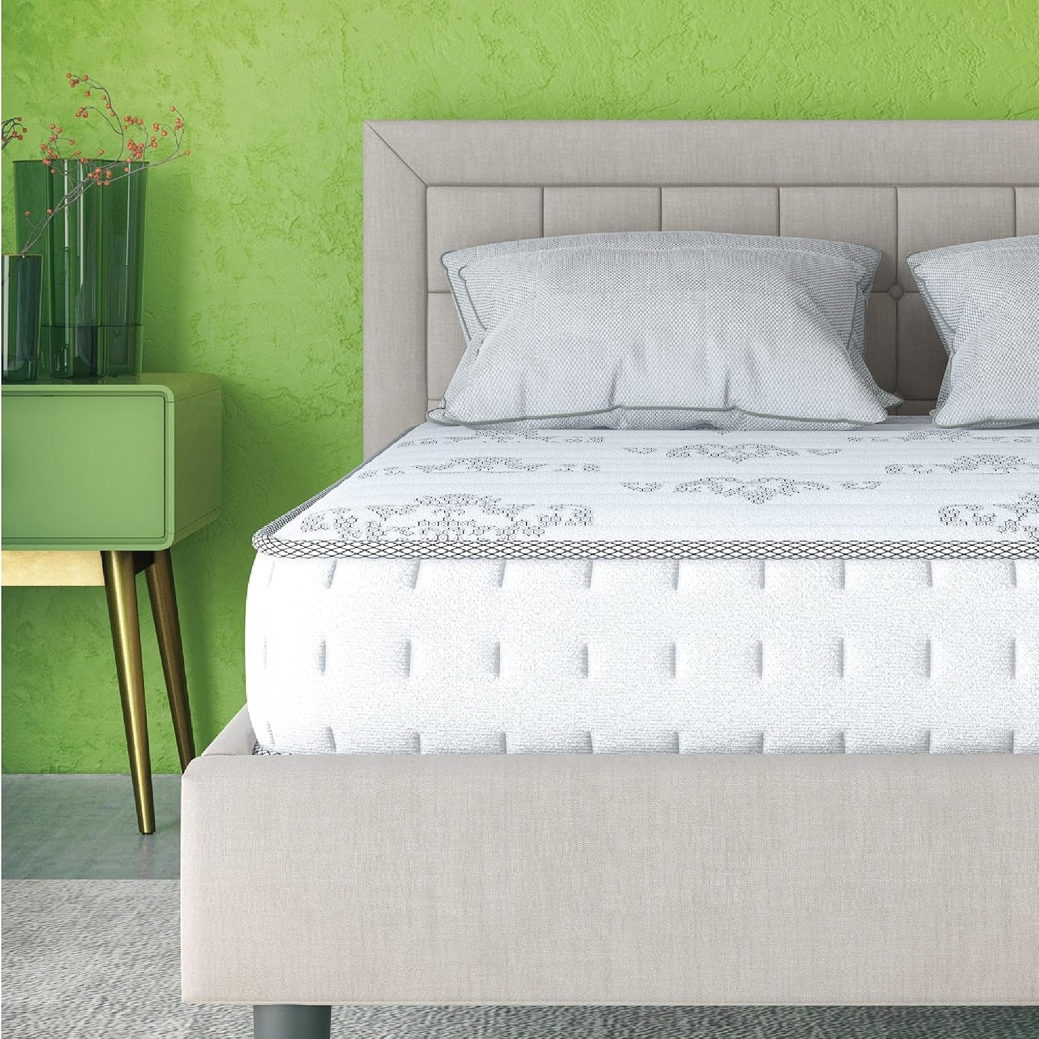 Straight-on front view of mattress on a beige upholstered bed with tufted headboard, two pillows and green textured wall.